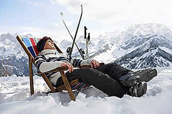 Skier resting on deckchair in mountains
