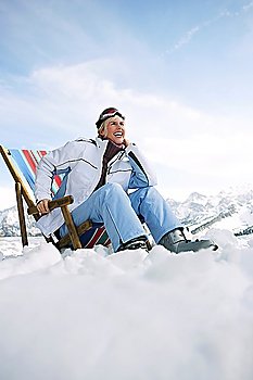Female skier sitting on deckchair in mountains low angle view