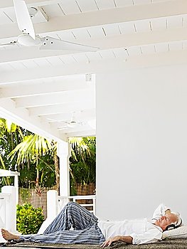 Man wearing headphones lying down on verandah