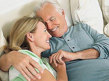 Couple embracing lying in bed elevated view
