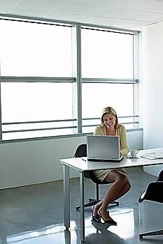 Business woman using laptop sitting at office desk