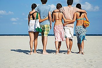 Group of teenagers (16-17) walking on beach back view