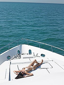 Young woman in bikini sunbathing on yacht elevated view