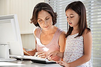 Daughter helping mother use computer at home