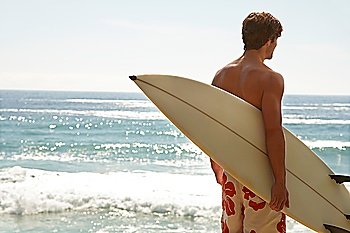 Man holding surfboard by ocean back view