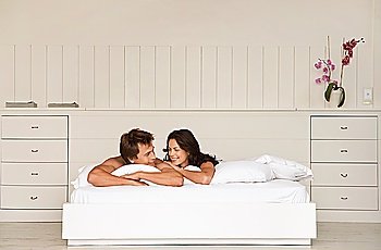 Couple lying in bed head and shoulders in bedroom