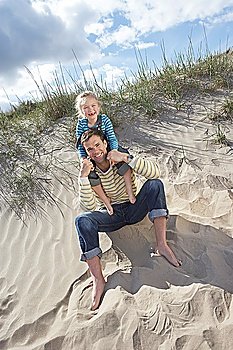 Girl (5-6) sitting on father´s shoulders on beach portrait