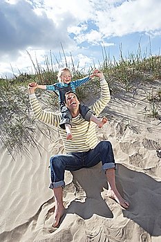 Girl (5-6) on fathers shoulders at beach
