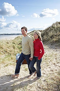 Couple holding hands walking on sand dune