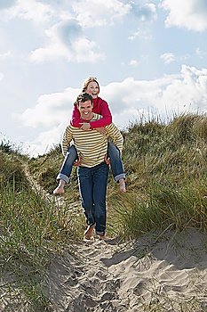 Man giving woman piggy back on sand dunes