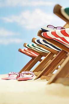 Row of deck chairs on beach focus on flip-flops on ground