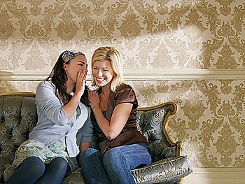 Two Young Women Whispering on Sofa