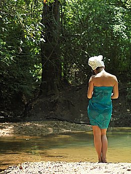 Young woman lake in forest with towel wrapped on head back view