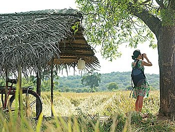 Young woman looking through binoculars bicycle under thatched roof