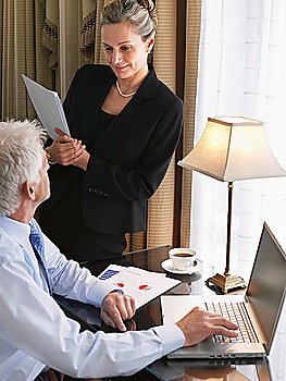 Business man using laptop business woman sitting on desk reading documents elevated view