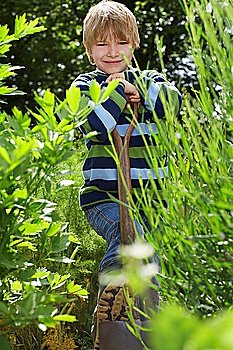 Boy (5-6) with spade surrounded by plants, portrait