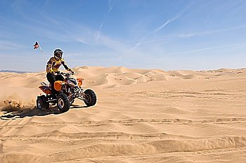 Young Man Riding ATV Over Sand Dune