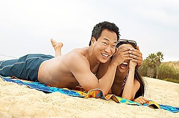 Man on Beach Covering His Girlfriend´s Eyes with His Hands