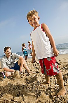 Boy Playing in Sand with Family at Beach