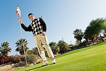 Young Man on Putting Green Holding Golf Flag
