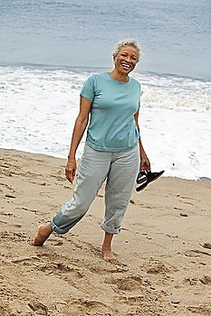 Smiling Woman Walking Barefoot on Beach