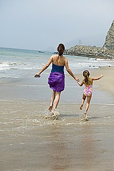 Mother and daughter skipping on beach