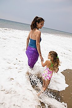 Mother and daughter walking through surf
