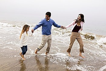 Family walking through surf on beach