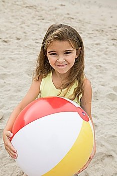 Portrait of girl holding beachball on beach, smiling