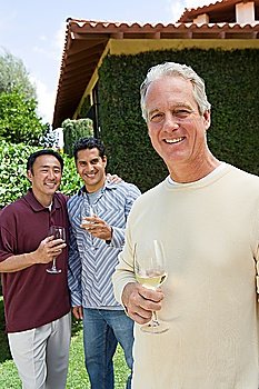 Three male friends drinking wine in garden, portrait