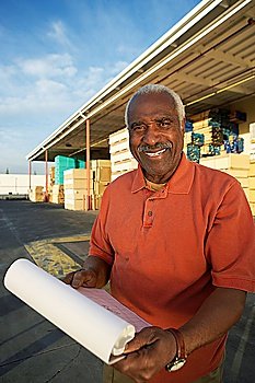 Manager with Paperwork by Loading Dock of Lumber Warehouse