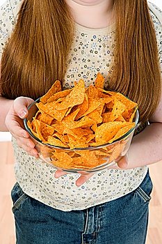 Girl standing, holding bowl of potato chips, mid section