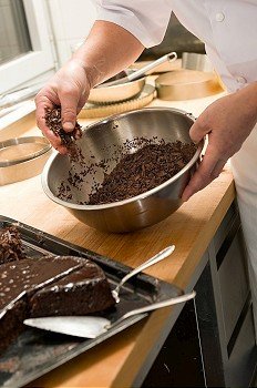 Chef decorating chocolate cake with dark brown icing sugar