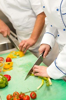 Close up of chefs cutting vegetables in hotel´s kitchen