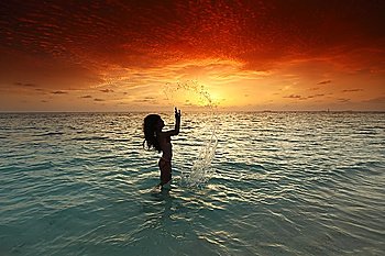 Woman splashing in sea on sunset