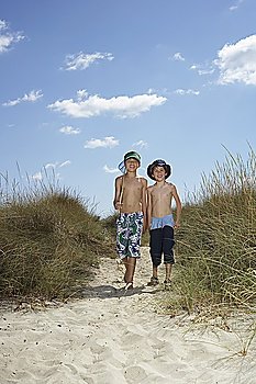 Two boys (6-11) walking in sand dunes with fishing net