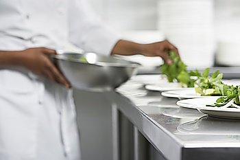 Chef preparing salad in kitchen, mid section