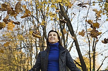 Woman under falling leaves in park