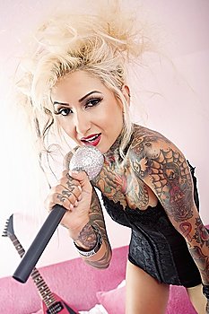 Portrait of a tattooed blond woman singing with microphone