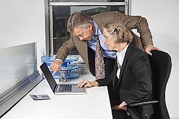 Side view of businesswoman and man looking at laptop screen at desk in office