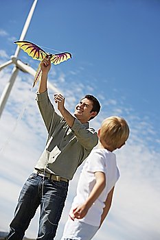 Father and son (7-9) playing with kite at wind farm