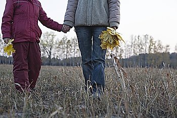 Mother and daughter holding hands in field