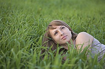 Young woman lies in a field of grass looking up