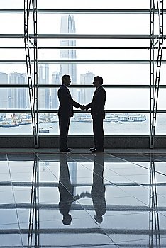 Silhouettes of two business men shaking hands