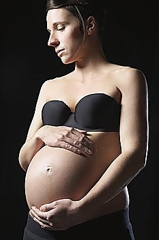 Pregnant woman touching abdomen, studio shot