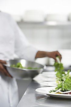 Chef preparing salad in kitchen, mid section
