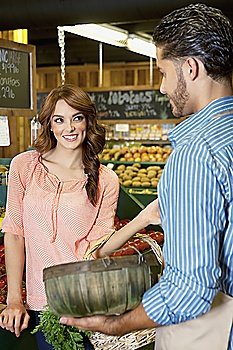 Happy young woman looking at store clerk in supermarket