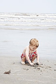 Boy crouching and playing with sand at water´s edge