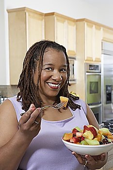 Woman eating salad in kitchen