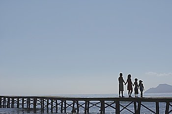 Silhouettes of parents and children (6-11) on jetty